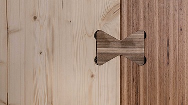 Foto einer Holz-Holz-Verbindung. Man sieht zwei Holzelemente, die wieder rum mit Holzstöpseln verbunden sind.