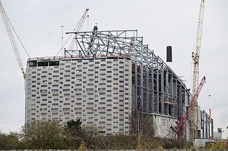 Luftaufnahme der grün-leuchtenden Fassade des Kraftwerks Lausward