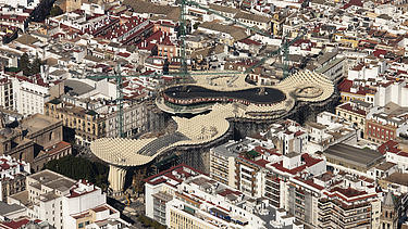 Foto einer Luftaufnahme von Sevilla. Man sieht die pilzartige Holzkonstruktion der Marktplatzüberdachung Metropol Parasol Sevilla.