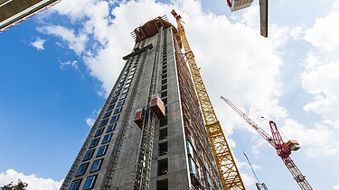 A picture of a high-rise building under construction, with a crane next to it