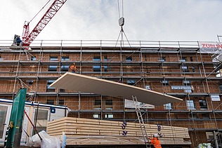Foto des Collegium Academicums in Heidelberg während der Montage. Man sieht das Abladen großer Holzelemente.
