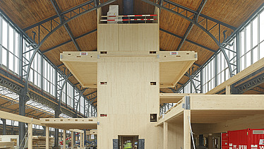 Foto des Hallenraumes des Gare Maritime Brüssel. Riesiger, offener Hallenraum mit Holzdachkonstruktion und Holzgebäude.