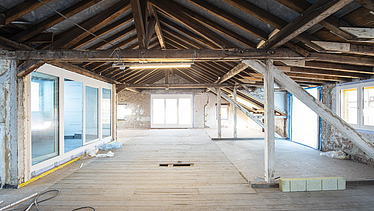 Lichtdurchflutete Fensterfront im Baubestand mit Ziegelsteinen und Holzelementen der Decke 