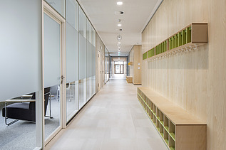 Innenaufnahme der Vinzenz-Pallotti-Schule in Friedberg. Man sieht einen Flur, eine Glas- und Holzwand und Aufbewahrungskisten an den Wänden.