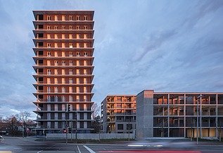 Exterior view of the CARL wooden high-rise in the evening at sunset