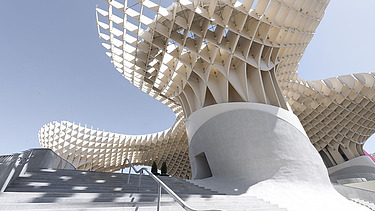 Foto einer großen Treppe. Oben sieht man die pilzartige Holzkonstruktion von Metropol Parasol Sevilla.