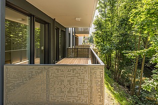 Nahaufnahme eines Balkon der Wohnanlage PURA. Balkon mit goldener Verkleidung