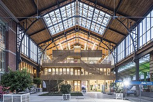 Foto des Hallenraumes des Gare Maritime Brüssel. Riesiger, offener Hallenraum mit Holzdachkonstruktion.