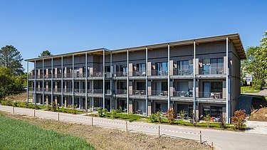 Rückansicht des Gebäudes mit vorgestellten Balkonen und Blick ins Grüne