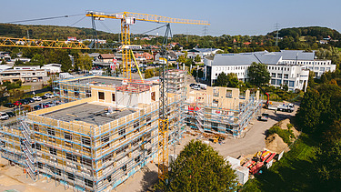 Foto der Uni Witten von außen. Man sieht die Montage großer Holzelemente aus der Vogelperspektive