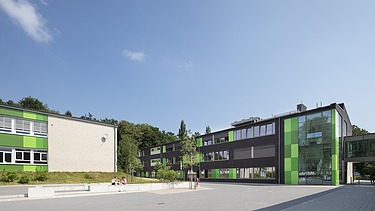 Moderne Architektur der berufsbildenden Schule mit grüner Fassade und großzügigem Eingangsbereich