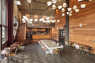 Wood-style cafeteria with lots of white pendant lights and a staircase
