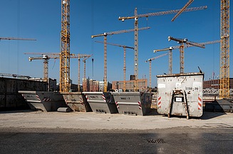 A picture of a building site with lots of cranes in the background and site huts in the foreground