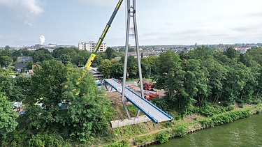 Drone shot of the Hertha Peters Bridge construction site, a crane lifts the steel structure