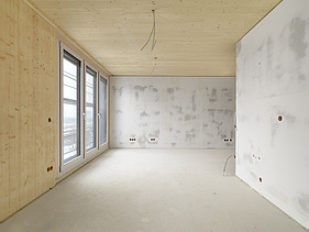 Foto des Gebäudes SKAIO Stadtsiedlung in Heilbronn. Man sieht einen Innenraum  mit Holzoberflächen und Betonwänden.