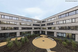 Grüner Schulhof mit umliegenden Gebäude