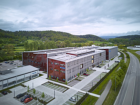 Luftaufnahme eines Gebäudekomplexes aus Holz mit roter Fassadengestaltung.