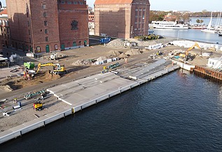Luftaufnahme der Baustelle am Hansakai Stralsund mit Kran und Bauelementen.“