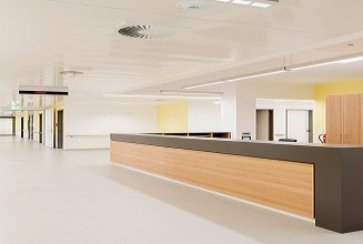 A photo of a hospital corridor with a reception desk