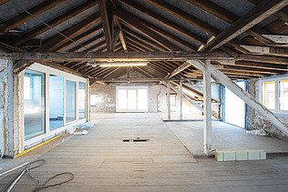 A light-filled window front in the existing building, featuring bricks and wooden ceiling elements 