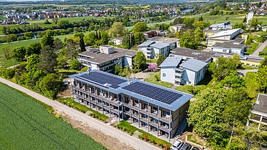 Luftbild des Gebäudes mit Photovoltaikanlage eingebettet in eine grüne Umgebung
