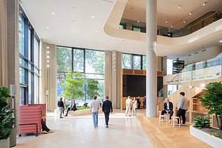Interior shot of an office building with a large open room containing people.