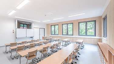 Klassenzimmer mit Betondecke und sichtbarer Holzoberfläche der Innenwände