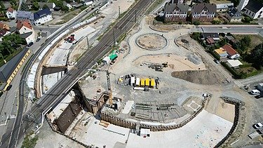 Aerial view of a construction site with railroad line and underpass