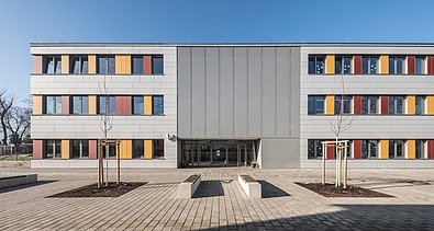 Image of the exterior view of Community School 6 in Erfurt. White building with yellow and red elements