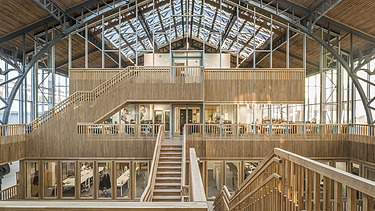 Foto des Hallenraumes des Gare Maritime Brüssel. Riesiger, offener Hallenraum mit Holzdachkonstruktion.