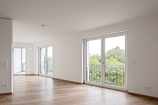 Example room in the HUGO Komfort residential complex in Bayreuth with parquet flooring and floor-to-ceiling windows