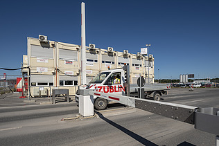 Picture of an access control point, with a car driving through and site huts in the background