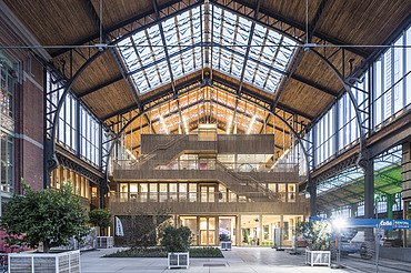 Foto des Hallenraumes des Gare Maritime Brüssel. Riesiger, offener Hallenraum mit Holzdachkonstruktion.
