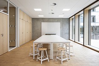 Innenaufnahme der Vinzenz-Pallotti-Schule in Friedberg. Man sieht einen möblierten Besprechungsraum und eine  Holz-Pfosten-Riegel-Fassade.