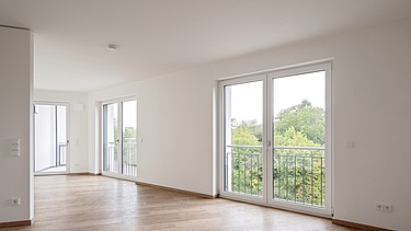 Example room in the HUGO Komfort residential complex in Bayreuth with parquet flooring and floor-to-ceiling windows