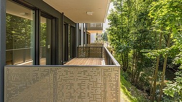 Nahaufnahme eines Balkon der Wohnanlage PURA. Balkon mit goldener Verkleidung