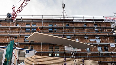 Foto des Collegium Academicums in Heidelberg während der Montage. Man sieht das Abladen großer Holzelemente.