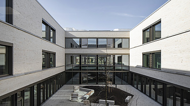 Außenaufnahme der Vinzenz-Pallotti-Schule in Friedberg. Man sieht ein großes, weißes Gebäude mit Flachdach und einem umliegenden Innenhof.