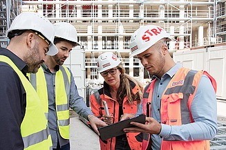 Foto Gruppe von vier Personen im Gespräch auf einer Baustelle