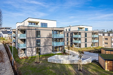 Außenansicht eines der beiden Wohngebäude mit Balkonen und einer Fassade aus Holz und Putz