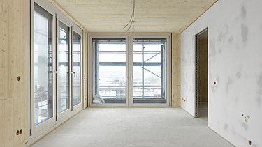 Foto des Gebäudes SKAIO Stadtsiedlung in Heilbronn. Man sieht einen Innenraum  mit Holzoberflächen und Betonwand.