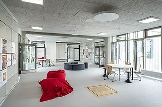 Bild von einem interaktiven Lernraum mit Sitzkissen, Leseecke und Tischen