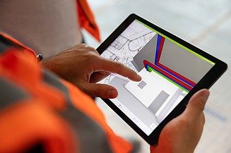 Foto Mitarbeiter auf einer Baustelle mit einem Tablet auf dem digitale Pläne zu sehen sind