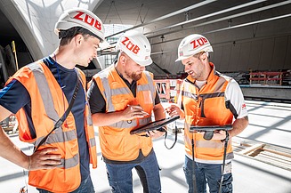 Arbeiter mit Sicherheitsbekleidung auf einer Baustelle, die sich besprechen