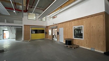 Foto des Innenausbaus einer Gewerbehalle. Man sieht LENO-Brettsperrholzwände und -decken.