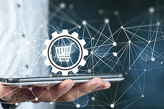 Photo of a man with a tablet in his hand above which a shopping cart symbol and the depiction of a network can be seen
