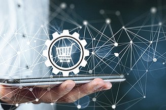 Photo of a man with a tablet in his hand above which a shopping cart symbol and the depiction of a network can be seen