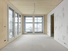 Foto des Gebäudes SKAIO Stadtsiedlung in Heilbronn. Man sieht einen Innenraum  mit Holzoberflächen und Betonwand.