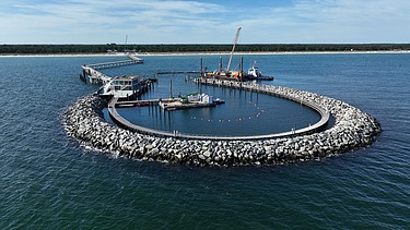 Detaillierte Ansicht einer ringförmigen Insel im Wasser, bestehend aus Steinen oder Betonblöcken, vor der Küste von Prerow.
