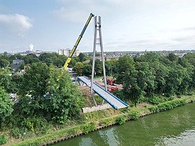 Drone shot of the Hertha Peters Bridge construction site, a crane lifts the steel structure
